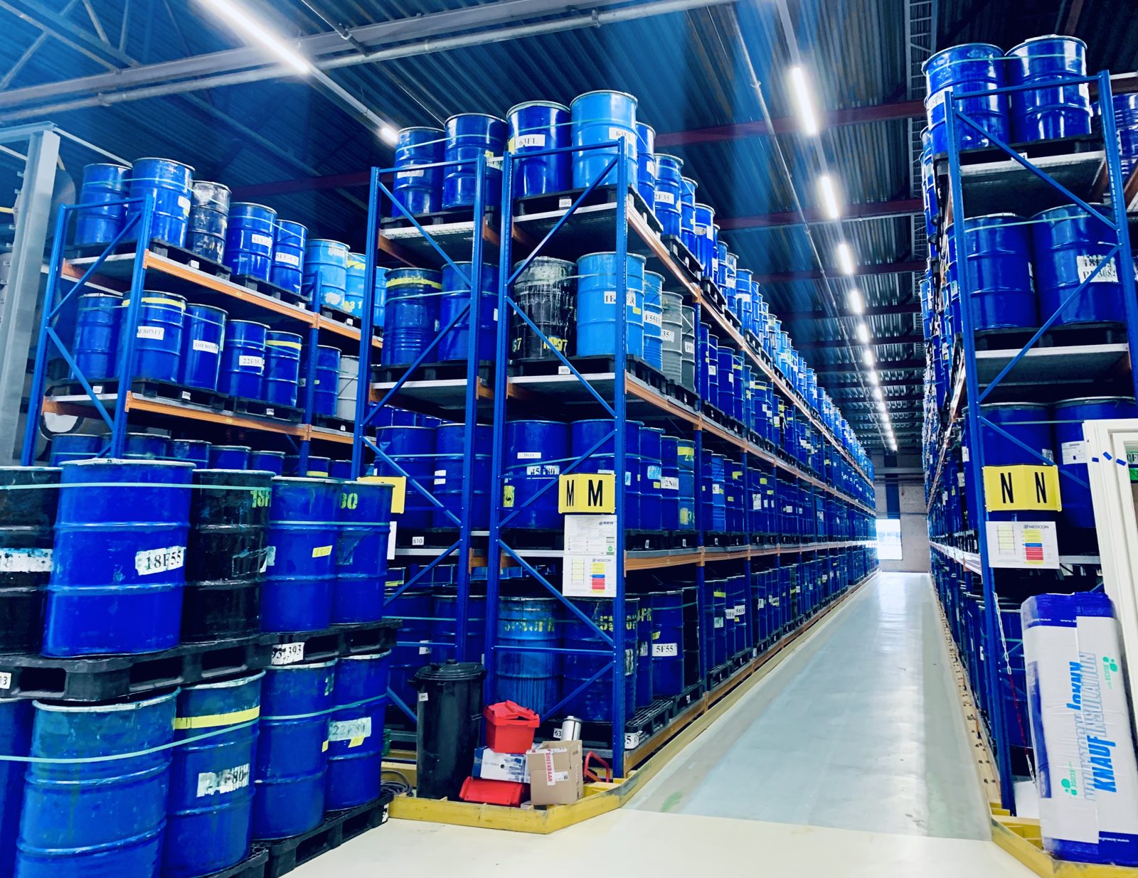 Hoge stellingen met vaten in een fabriek in Heerhugowaard onder LED-lichtlijnen